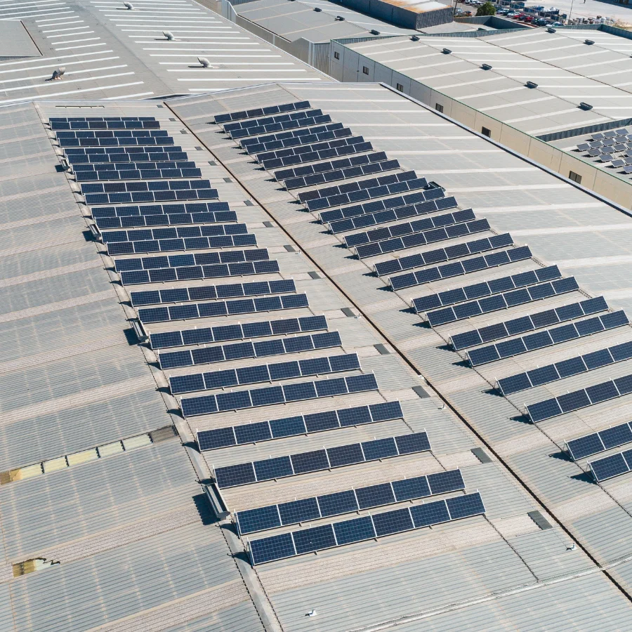 Vista aérea instalación placas solares sobre techo nave industrial.